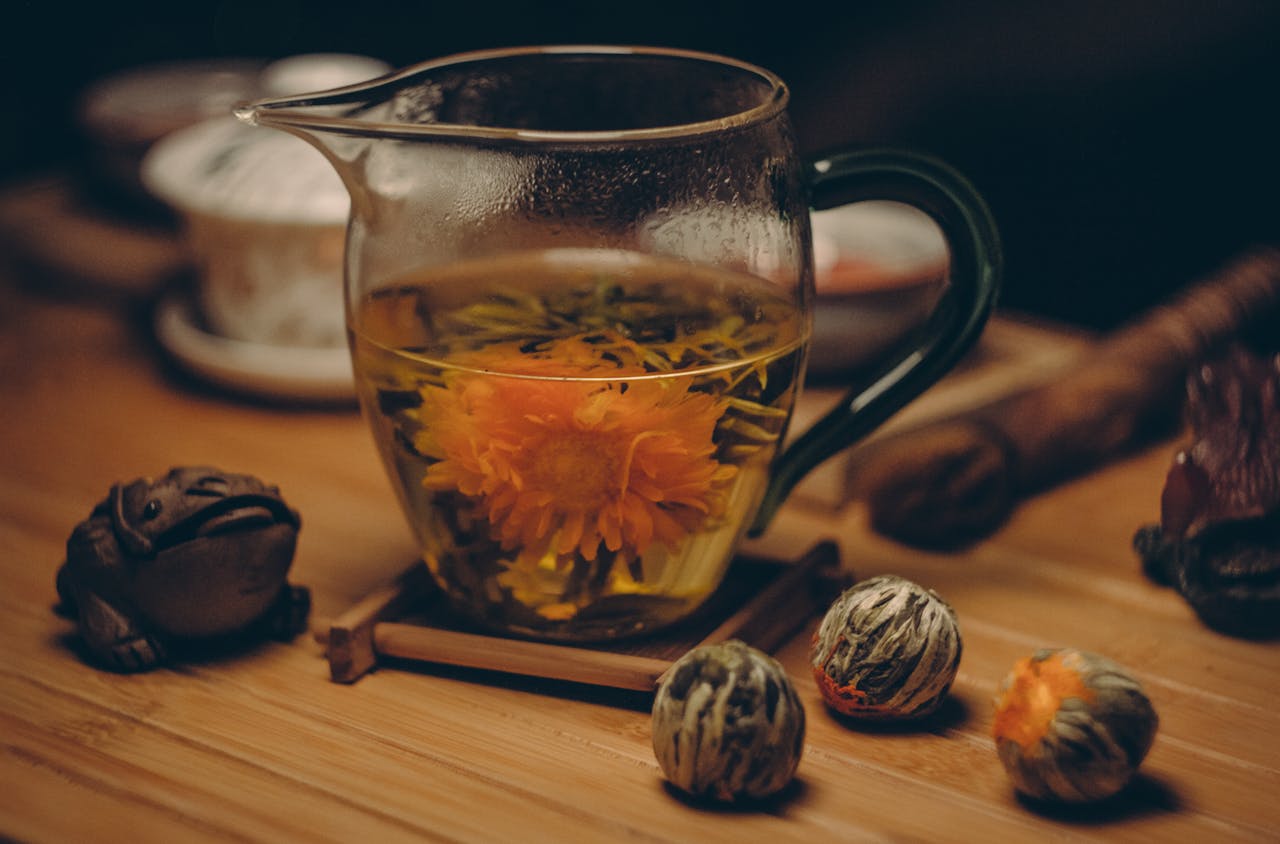digital A glass cup of chrysanthemum tea with blooming flower steeped in warm water on a wooden table.