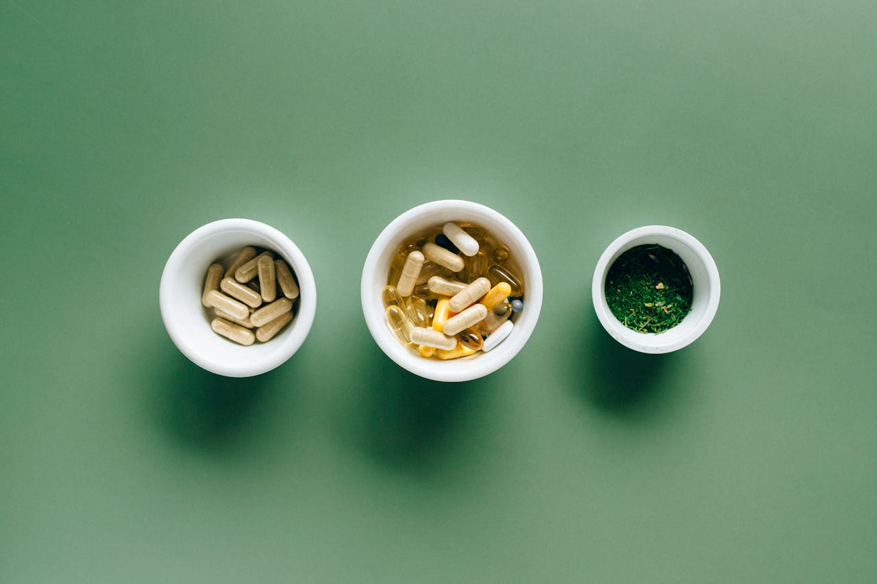 our-story Top view of bowls with capsules, herbs, and supplements on green surface for healthcare concept.